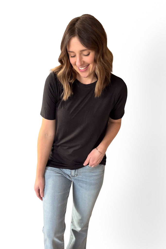 Woman wearing a black t-shirt and light blue jeans on a white background