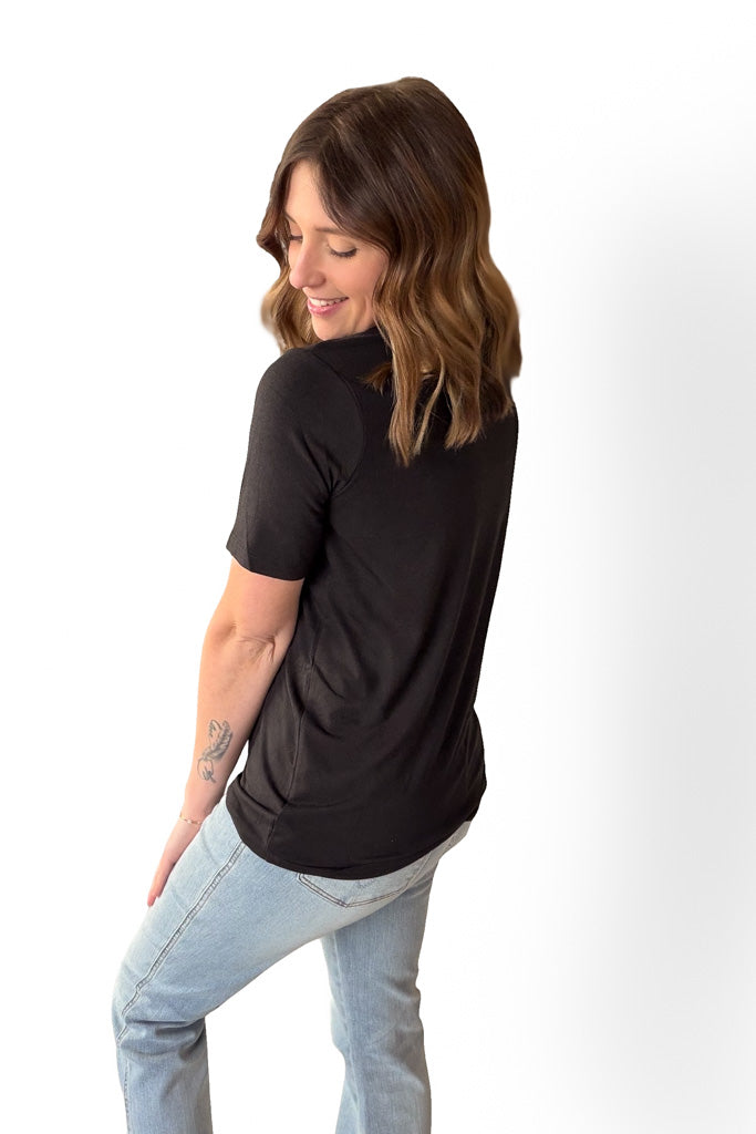 Woman wearing a black t-shirt and light blue jeans on a white background