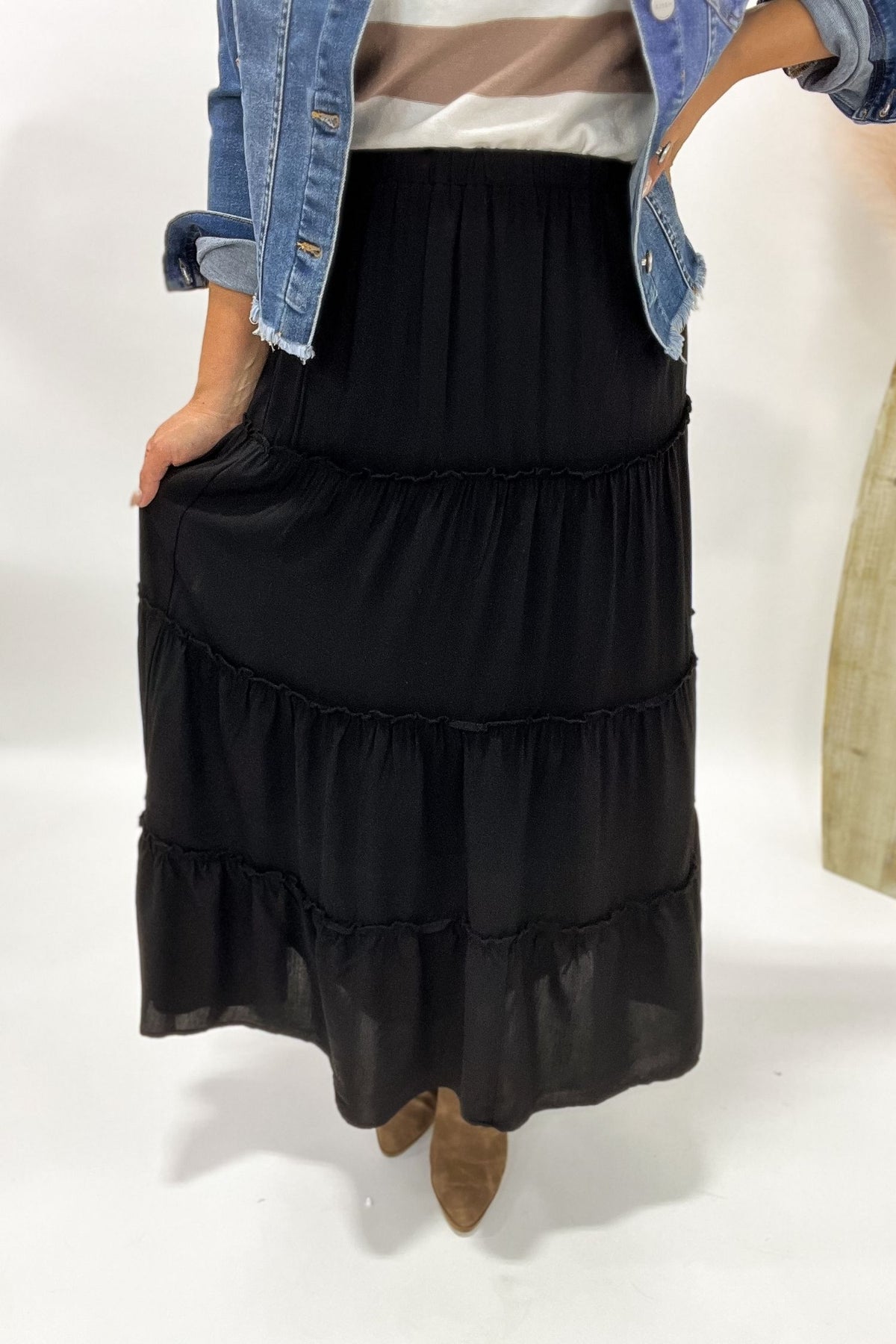 Person wearing a black tiered skirt with a plain background