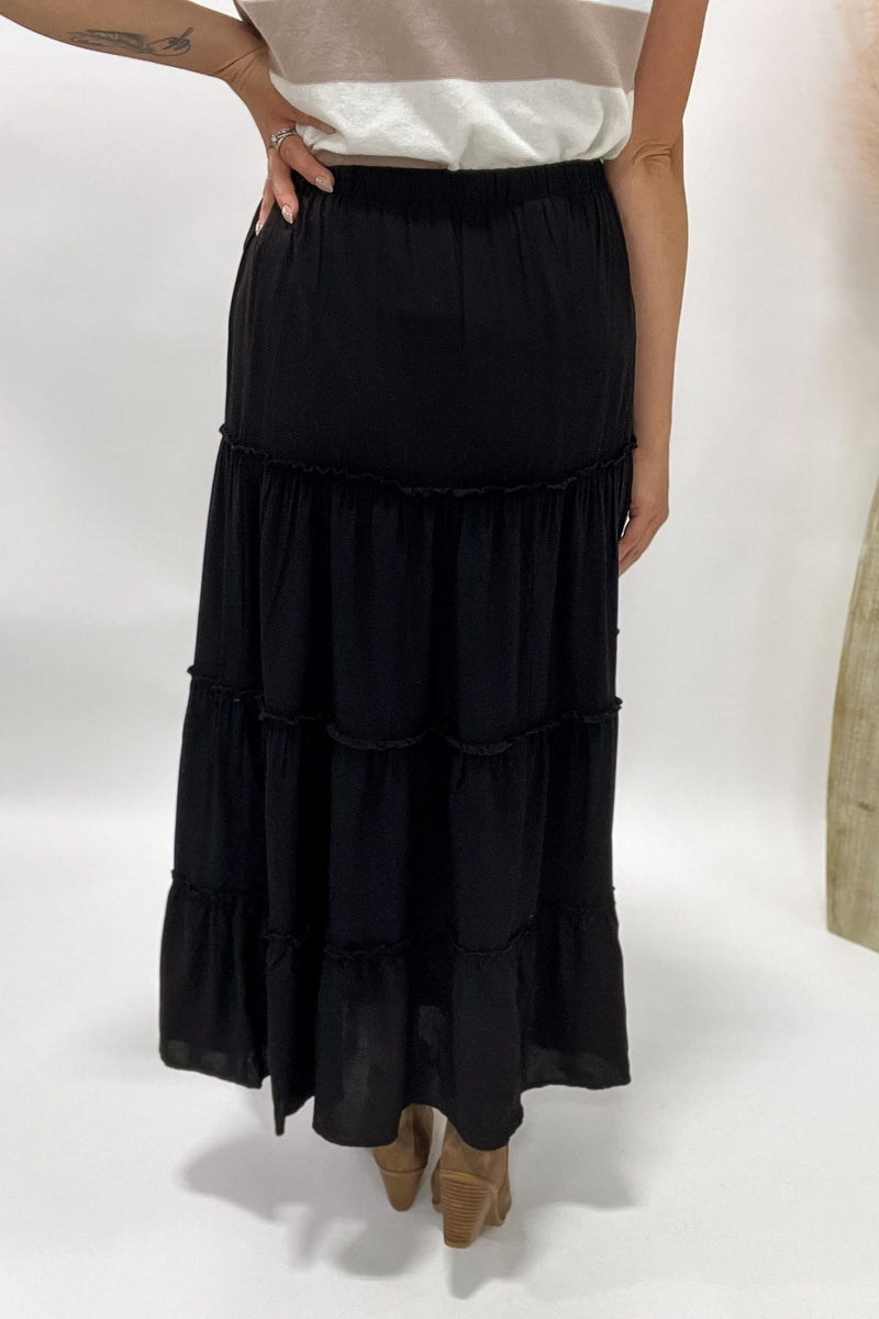 Person wearing a black tiered skirt on a white background