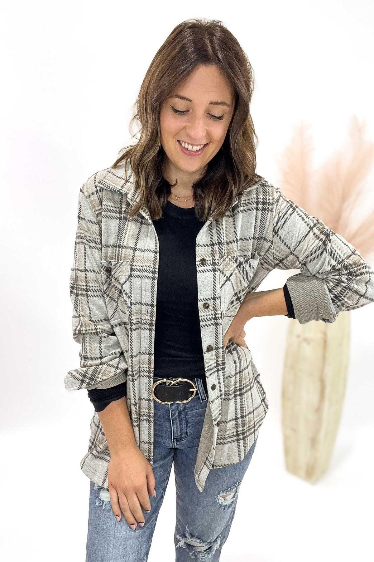 Woman wearing a plaid shirt over a black top with jeans on a white background