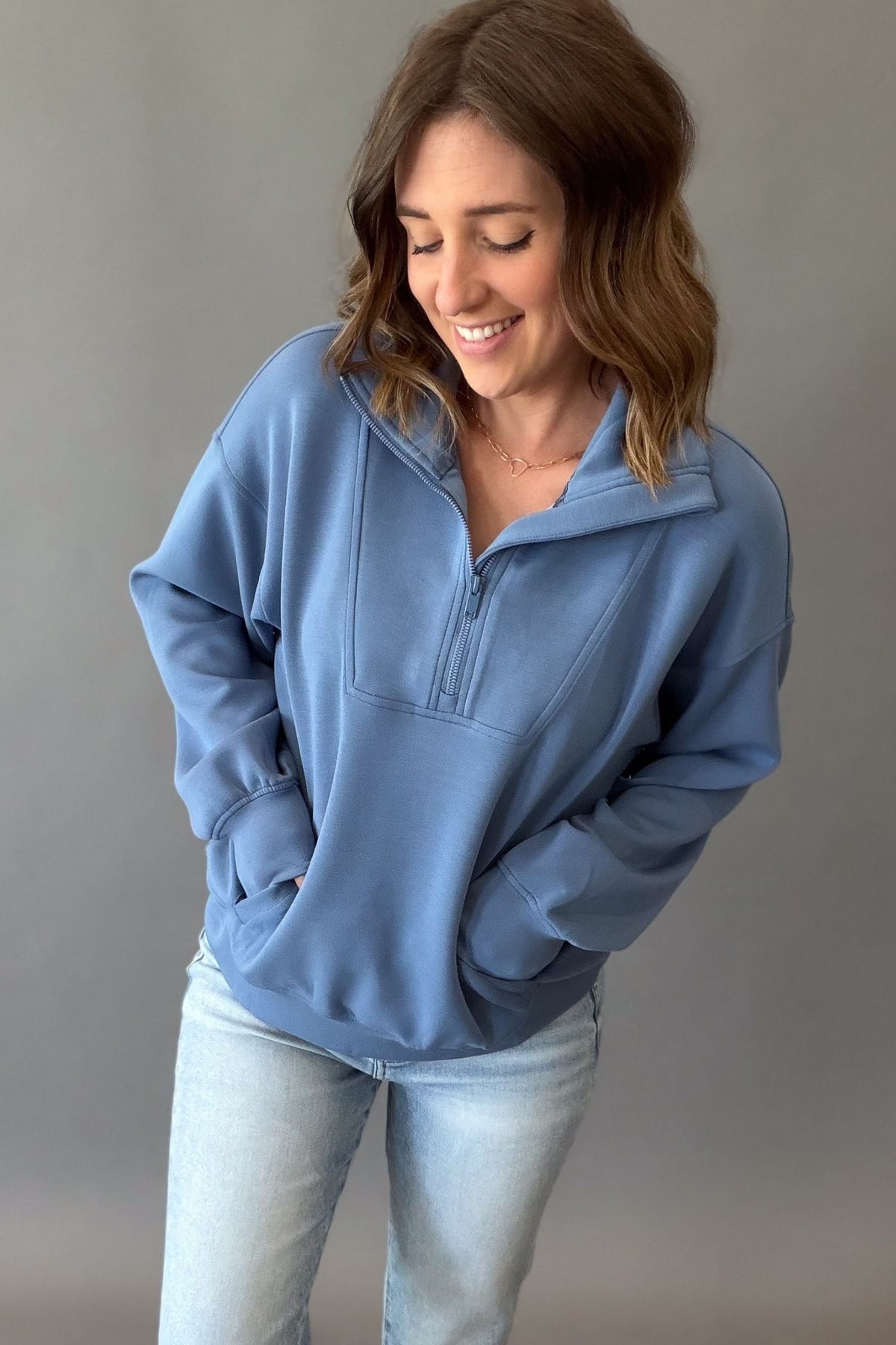 woman wearing a blue mock neck quarter zip showing side pockets.