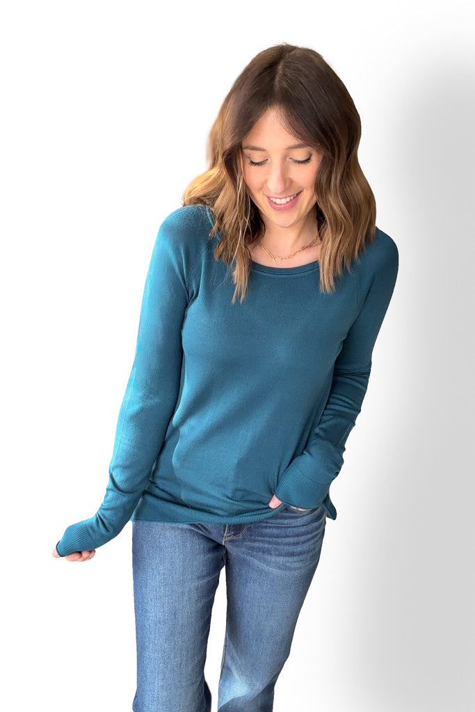 Woman wearing a blue long-sleeve top and blue jeans on a white background