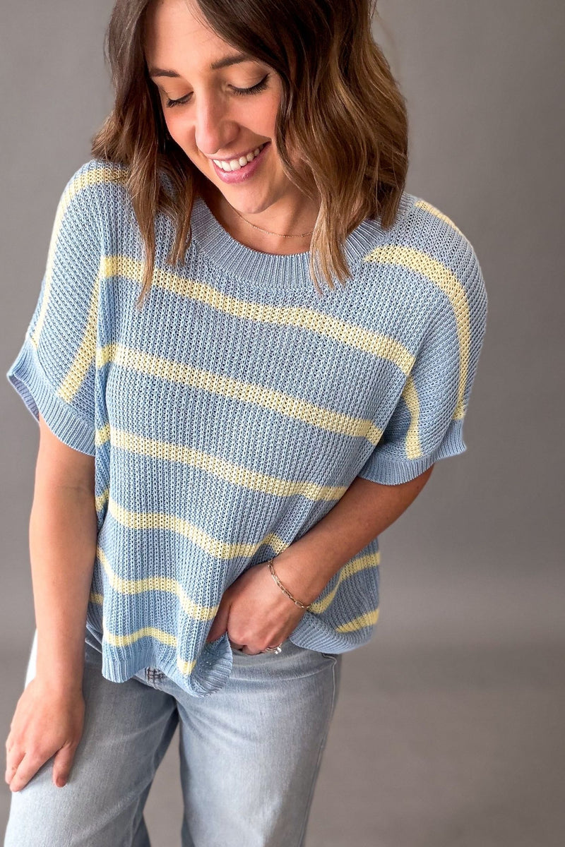 Woman wearing a blue and yellow striped sweater against a gray background showing the soft knit texture.
