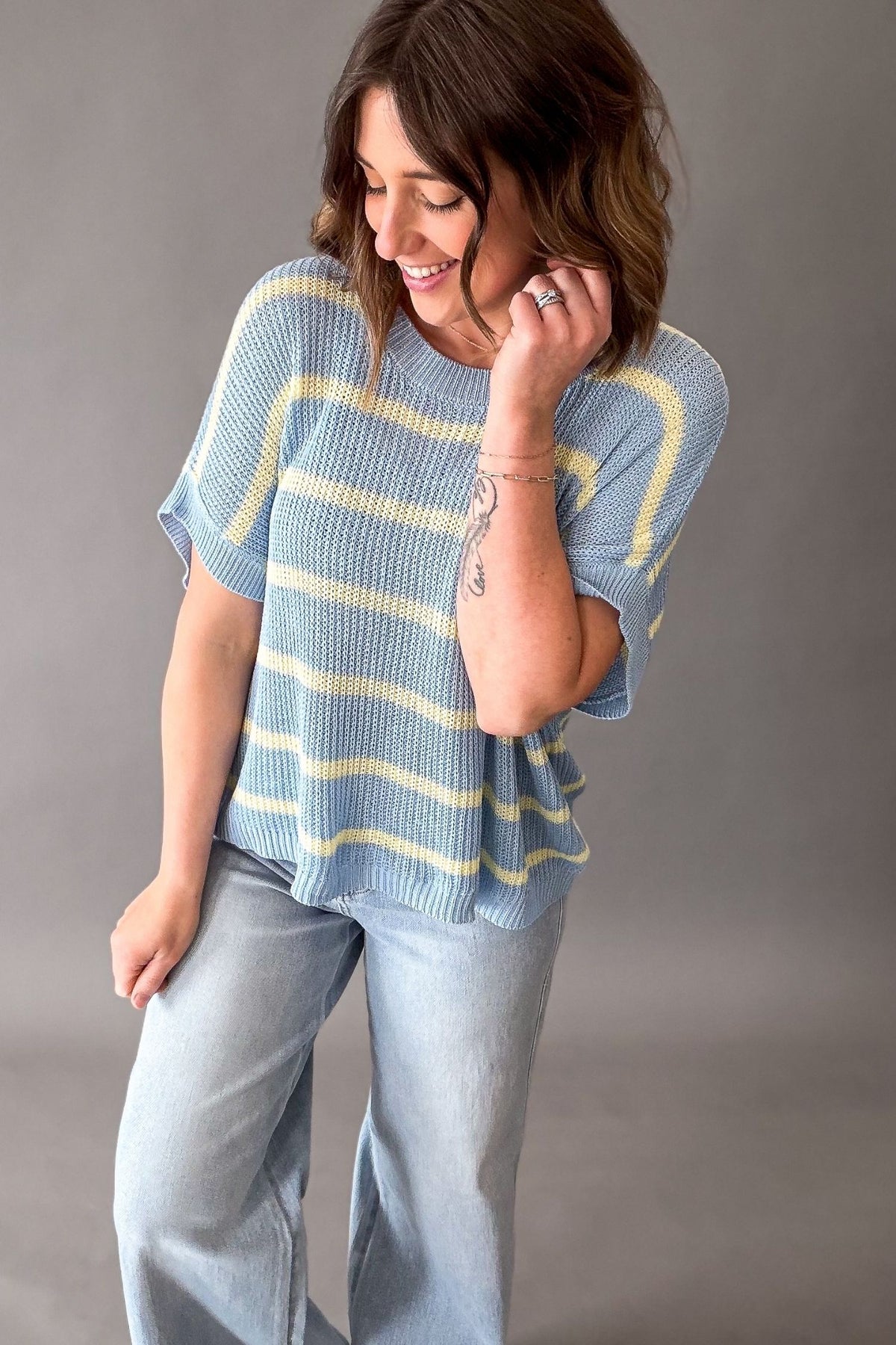 Woman wearing a blue and yellow striped shirt against a gray background showing the modest length and allover texture