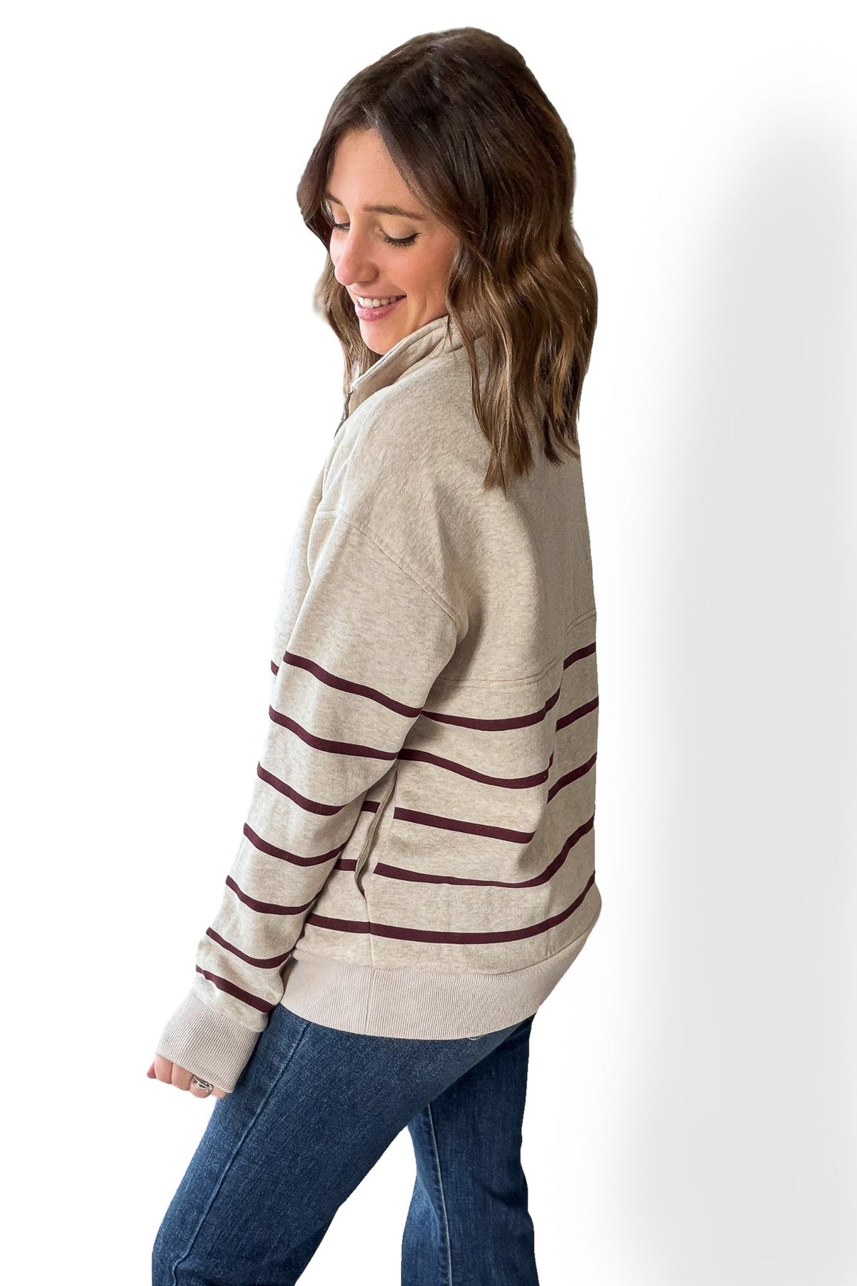 Woman wearing a beige sweater with burgundy stripes on a white background