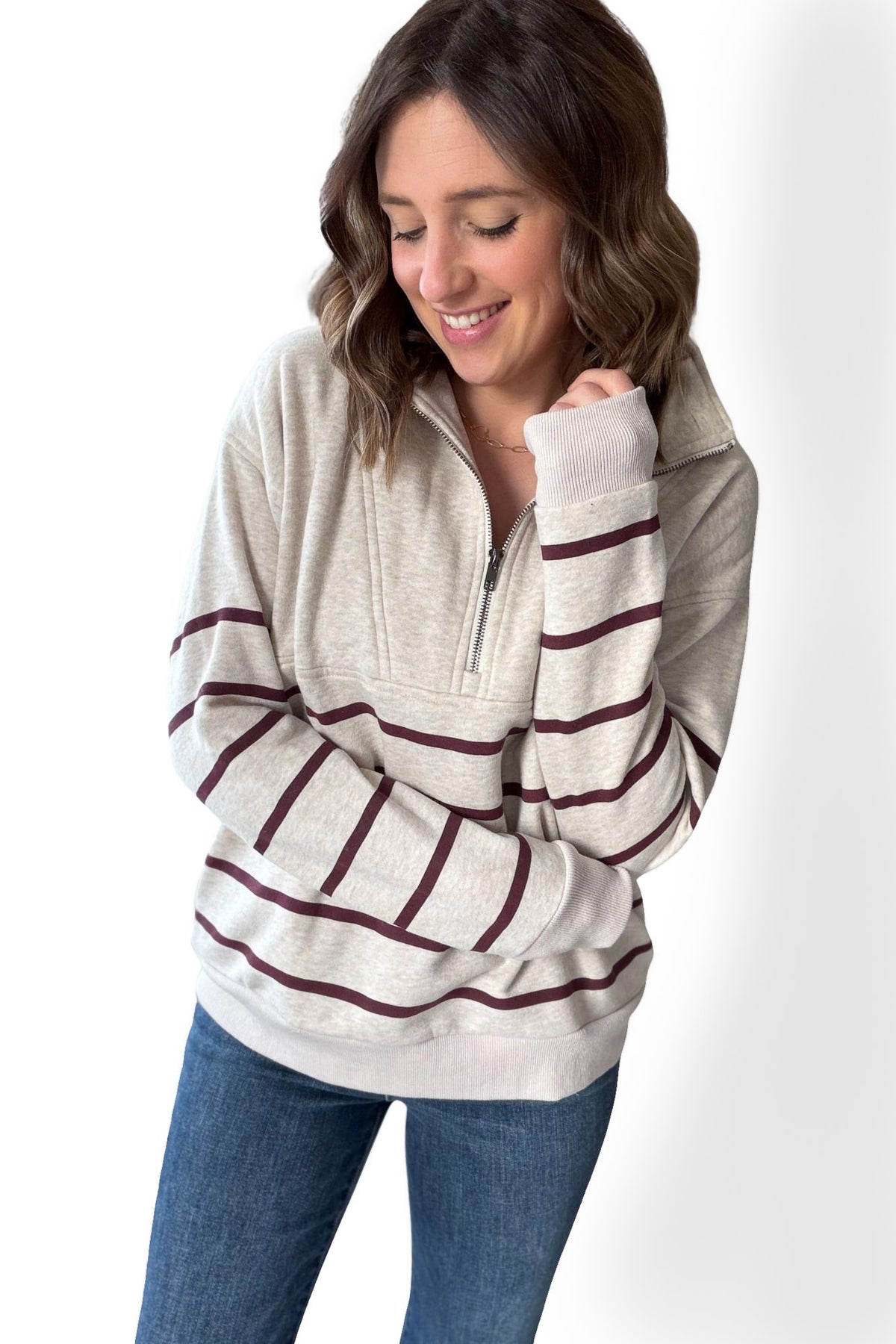 Woman wearing a striped long-sleeve half zip sweatshirt with a white background