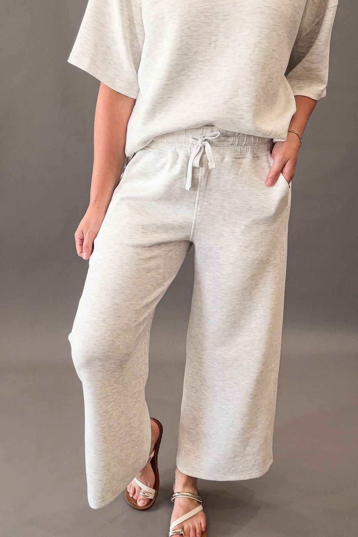 woman wearing a pair of cropped wide leg knit pants and a matching top on a grey background