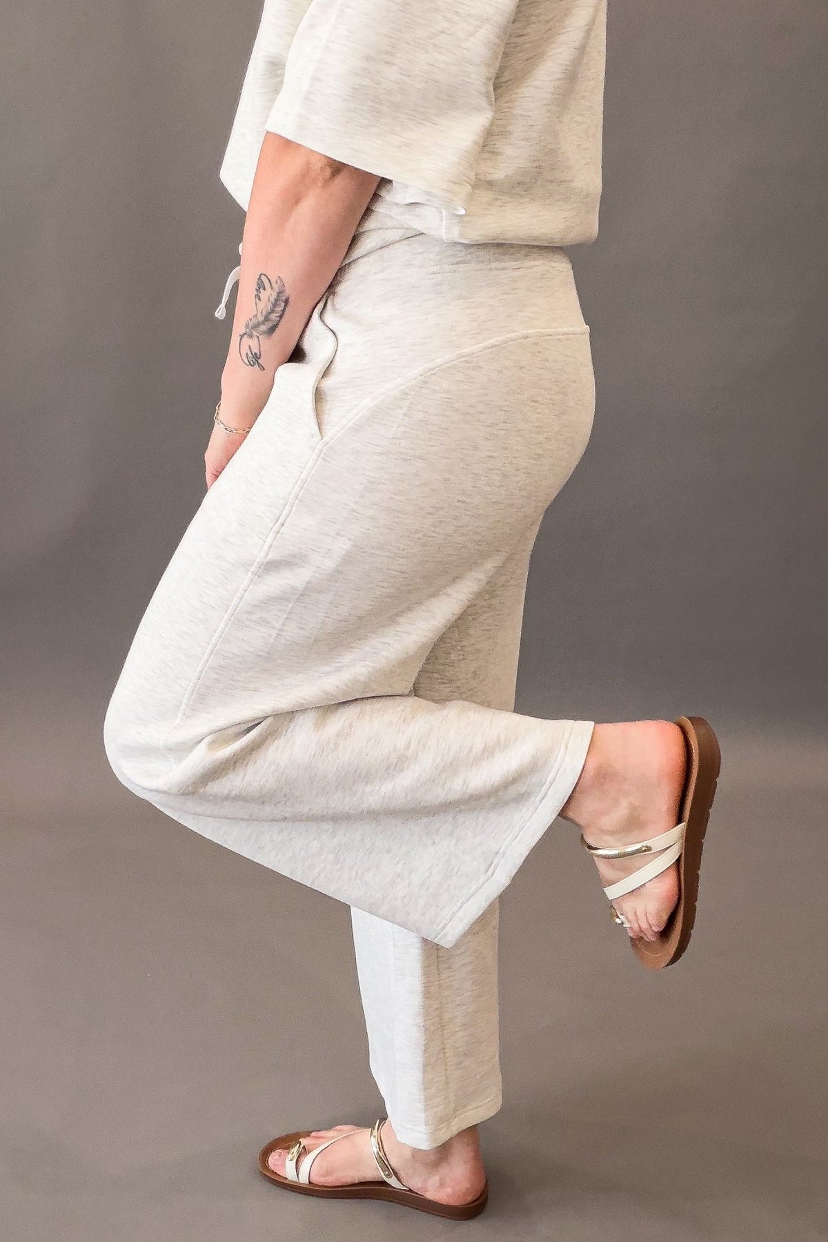 woman wearing a relaxed fit gray pants showing the side details