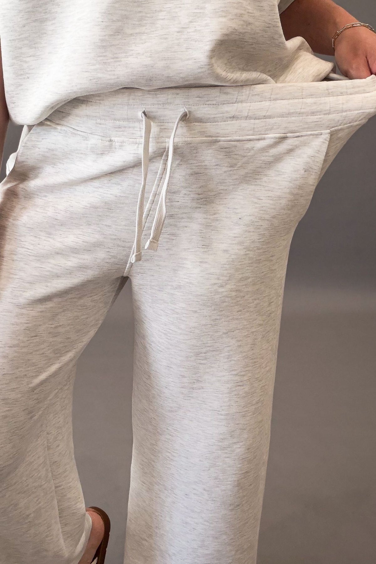 woman wearing a heather grey lounge set showing the stretchy elastic drawstring waistband
