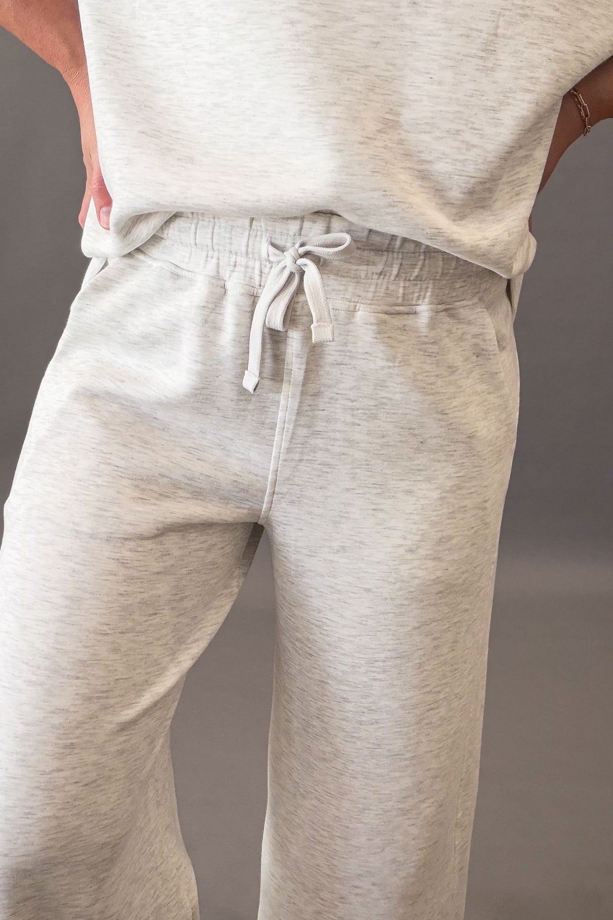 woman wearing a super soft light grey top and pants showing close up heather details and drawstring waist