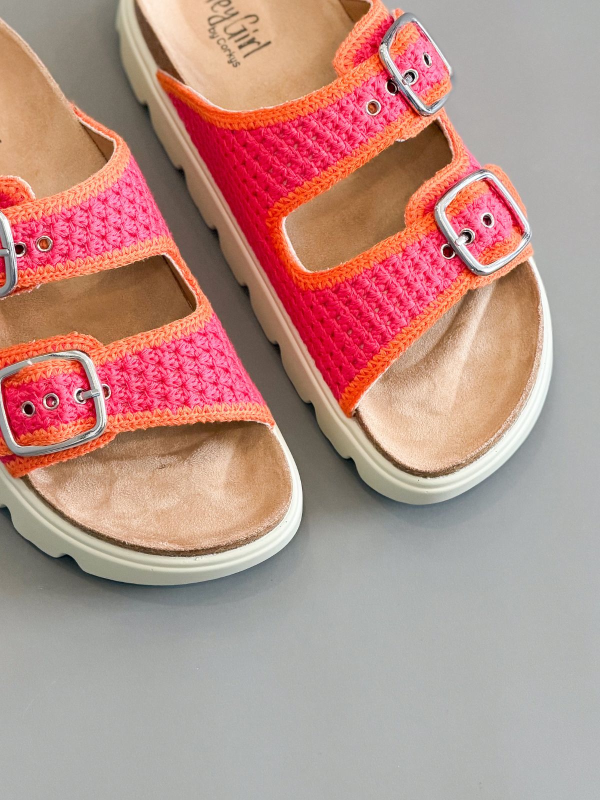 Pink sandals with orange straps on a gray background