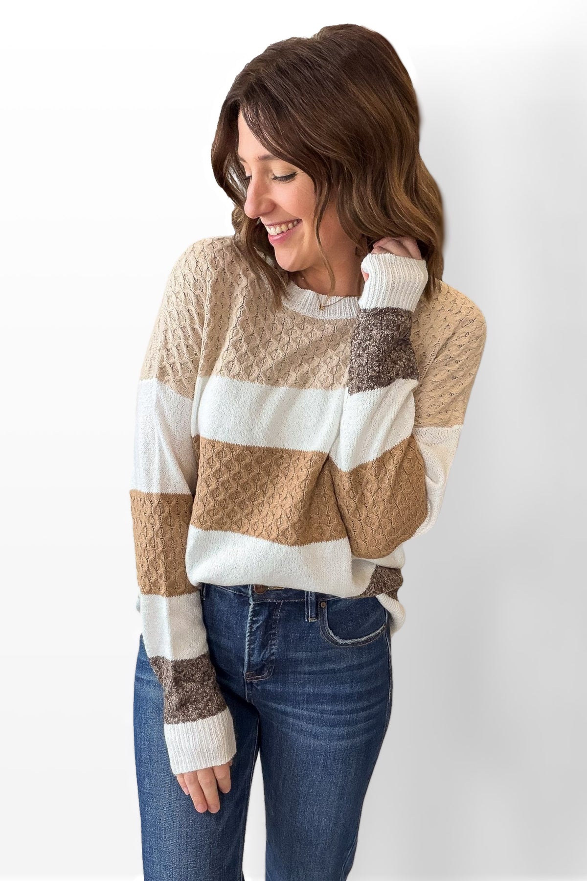 Woman wearing a striped sweater and jeans against a white background