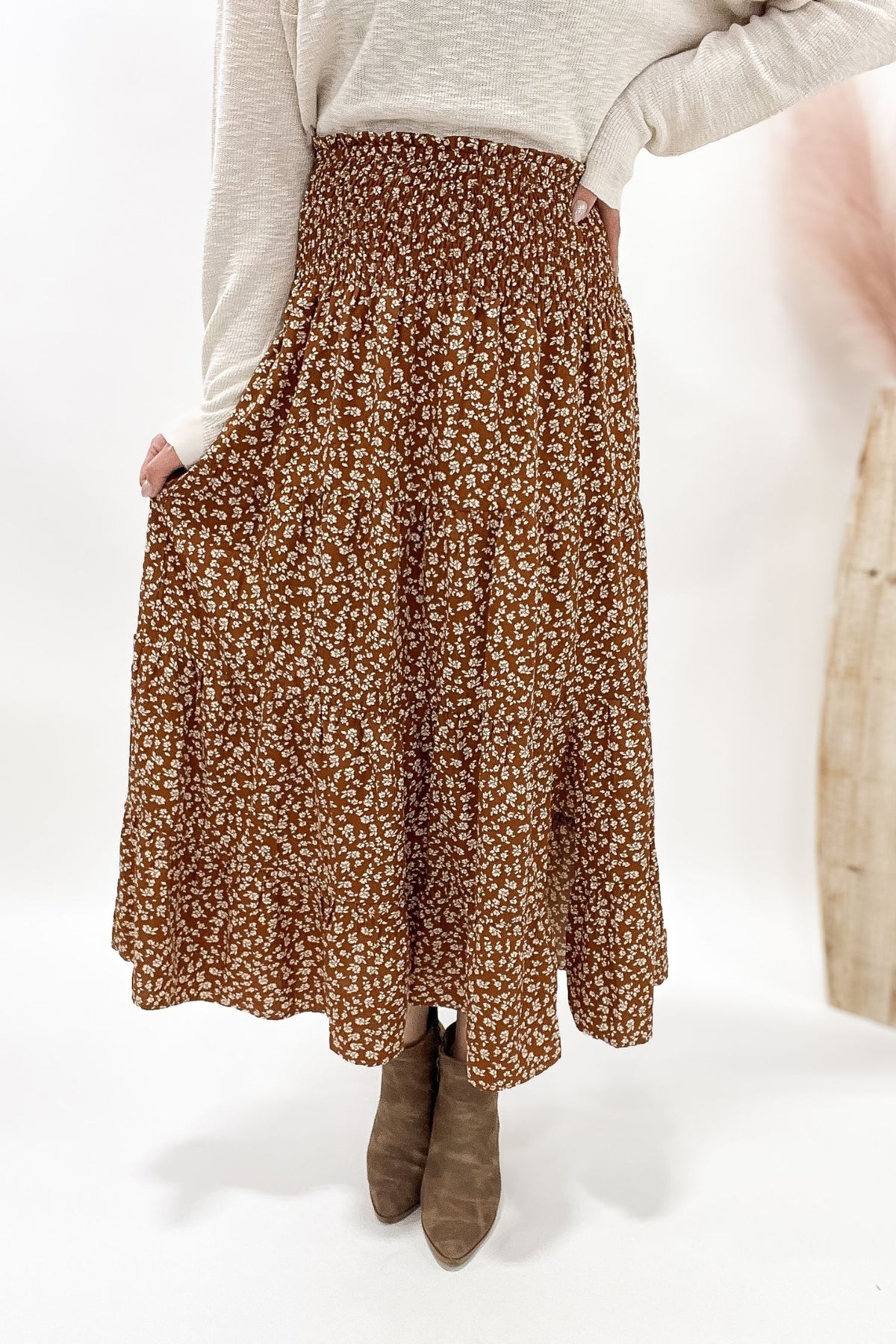Person wearing a camel floral skirt on a white background