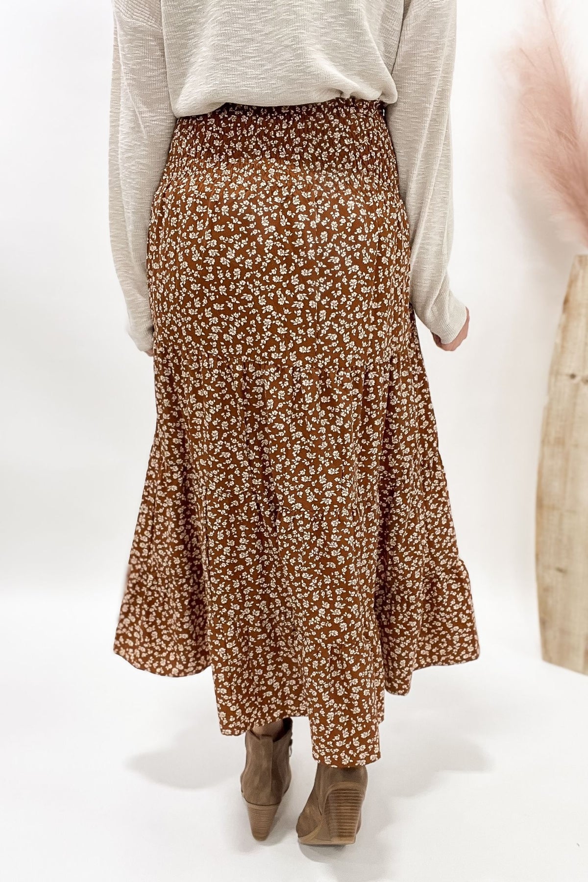 Person wearing a camel floral skirt on a white background