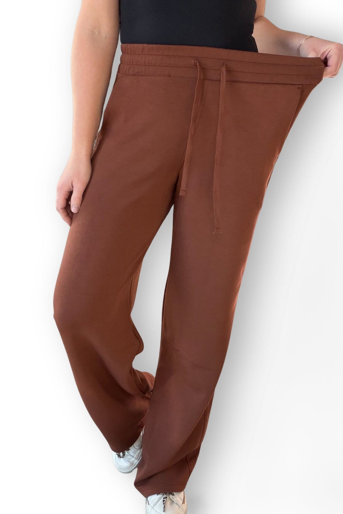 Chestnut scuba strait pants worn by a person on a white background showing stretch in the waistband