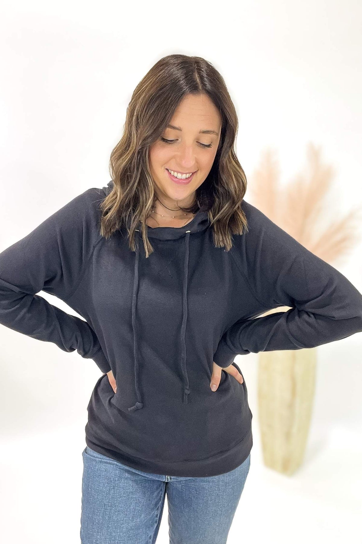 Woman wearing a charcoal hoodie and jeans on a white background