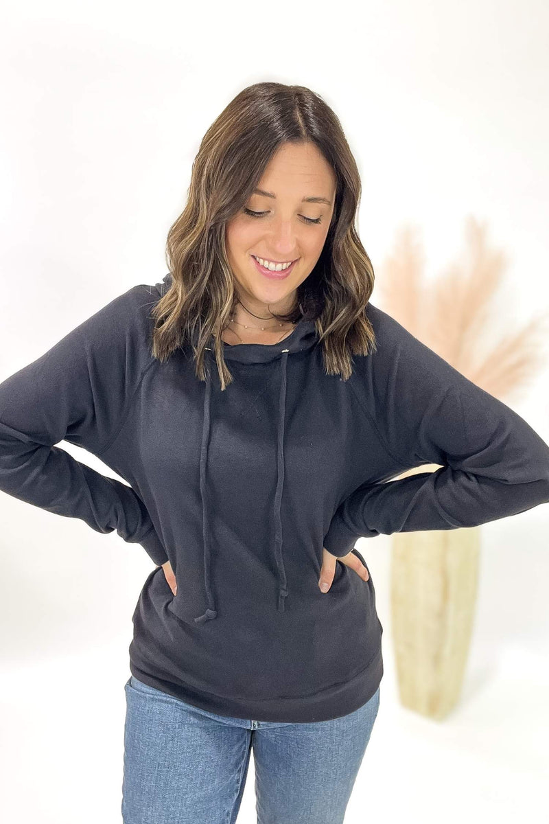 Woman wearing a charcoal hoodie and jeans on a white background