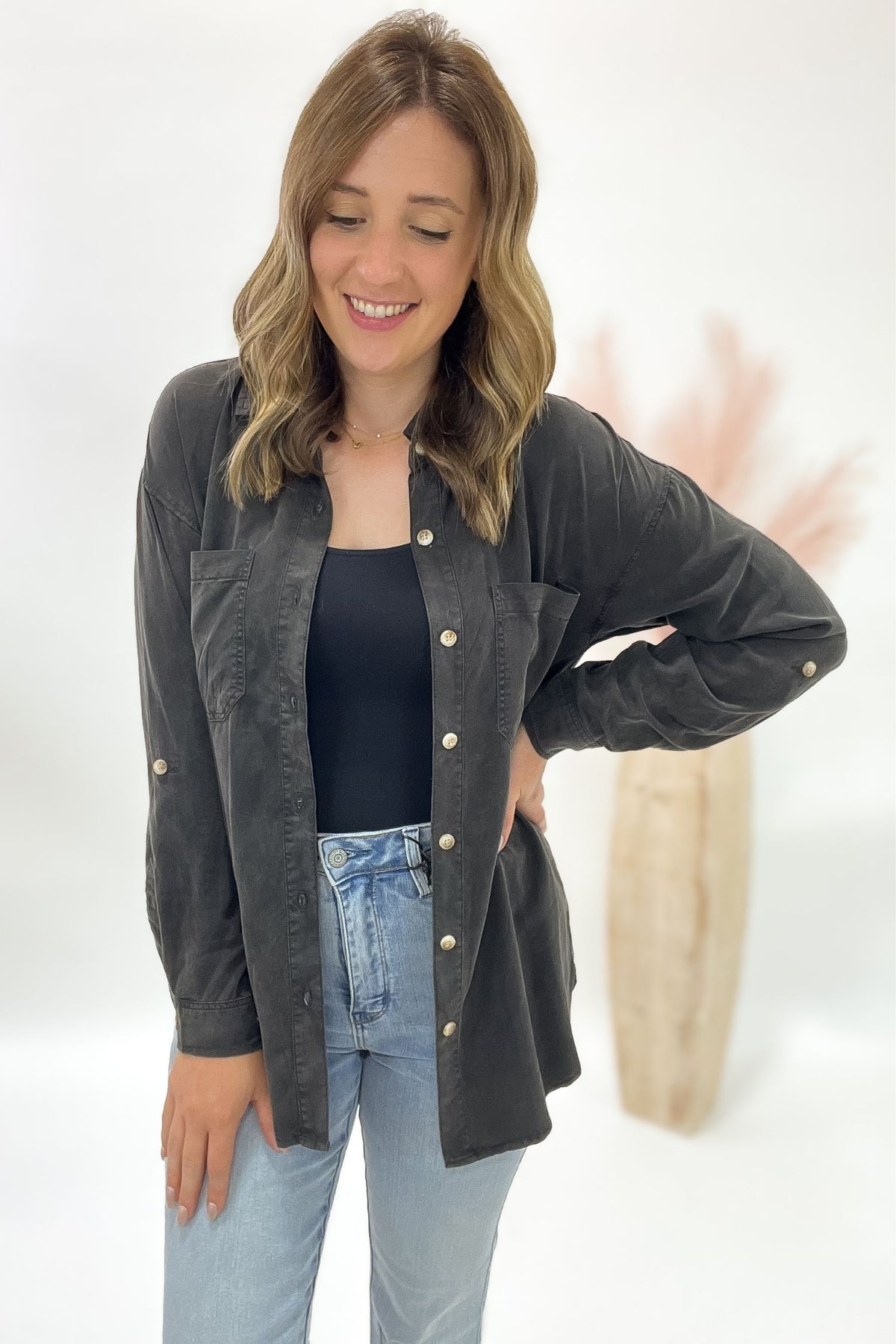 Woman wearing a dark gray button up with button details on a white background