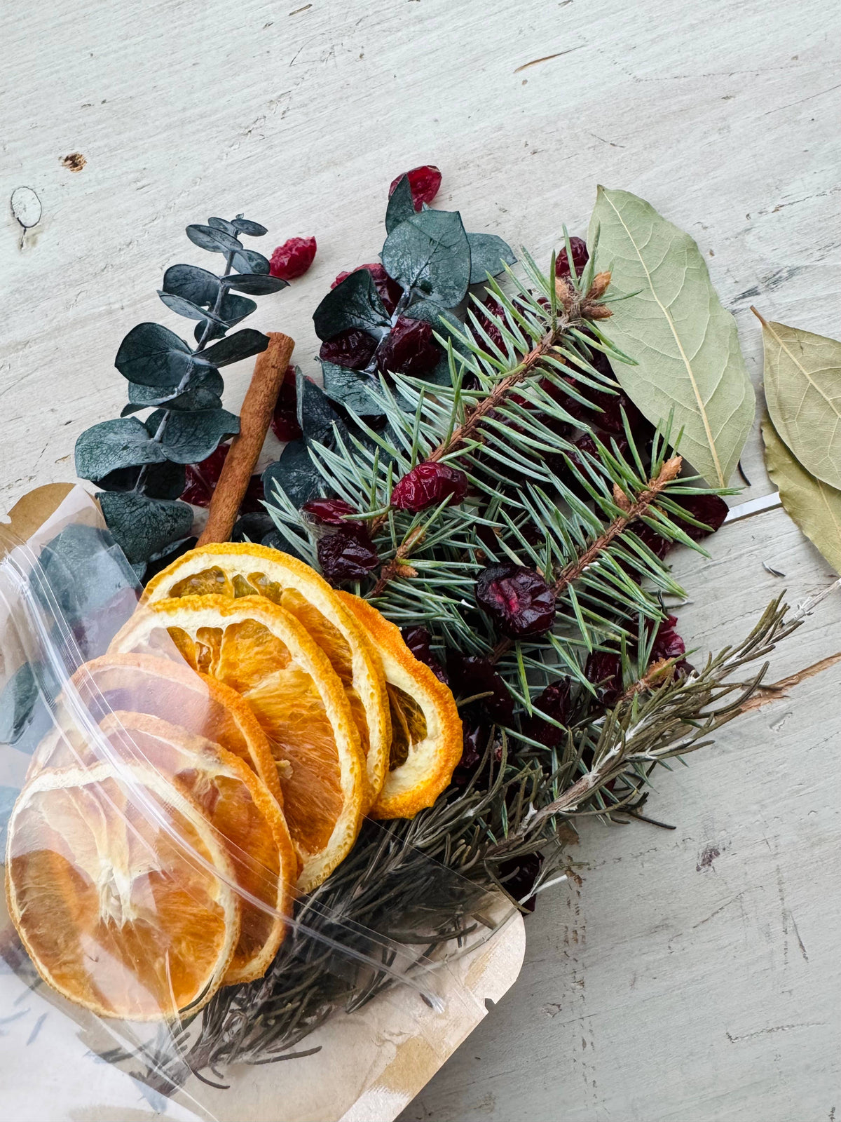 Dried oranges, cinnamon sticks, and greenery on a light surface