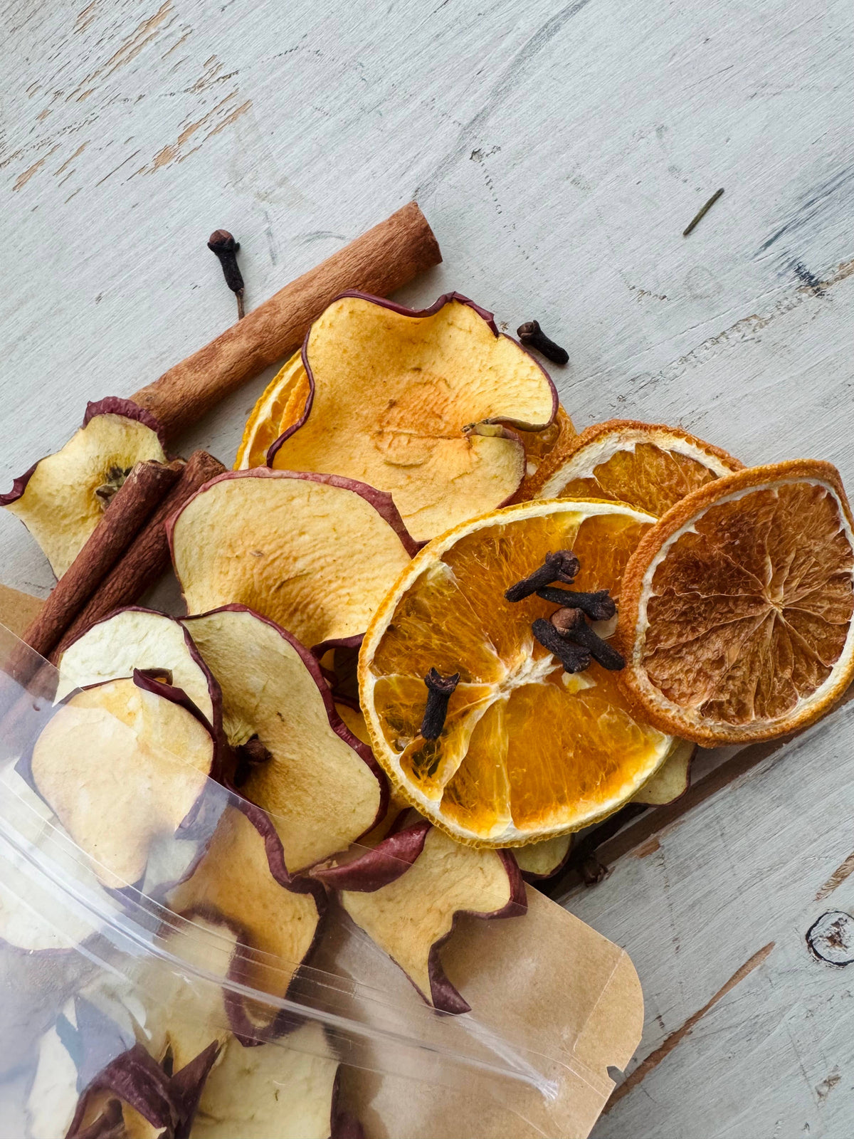 Dried fruit and cinnamon sticks in a clear container on a wooden surface
