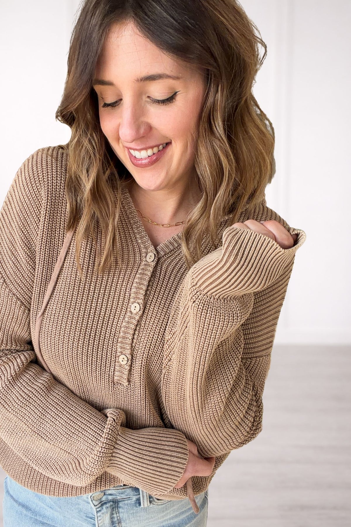 Woman wearing a light brown henley hoodie knit sweater