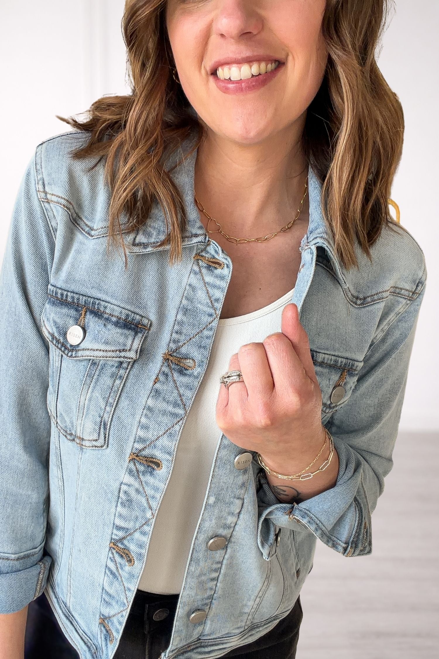 Person wearing a light blue denim jacket with a plain background