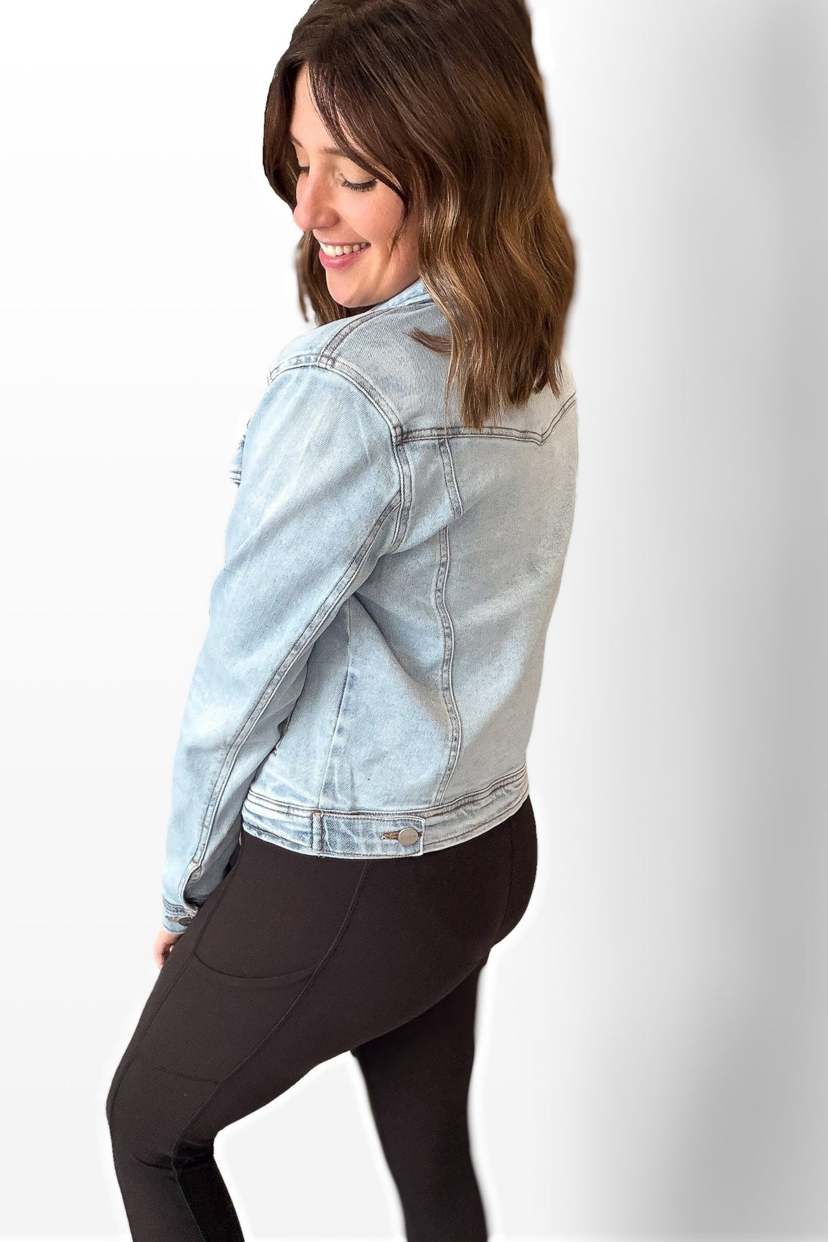 Woman wearing a light blue denim jacket on a white background