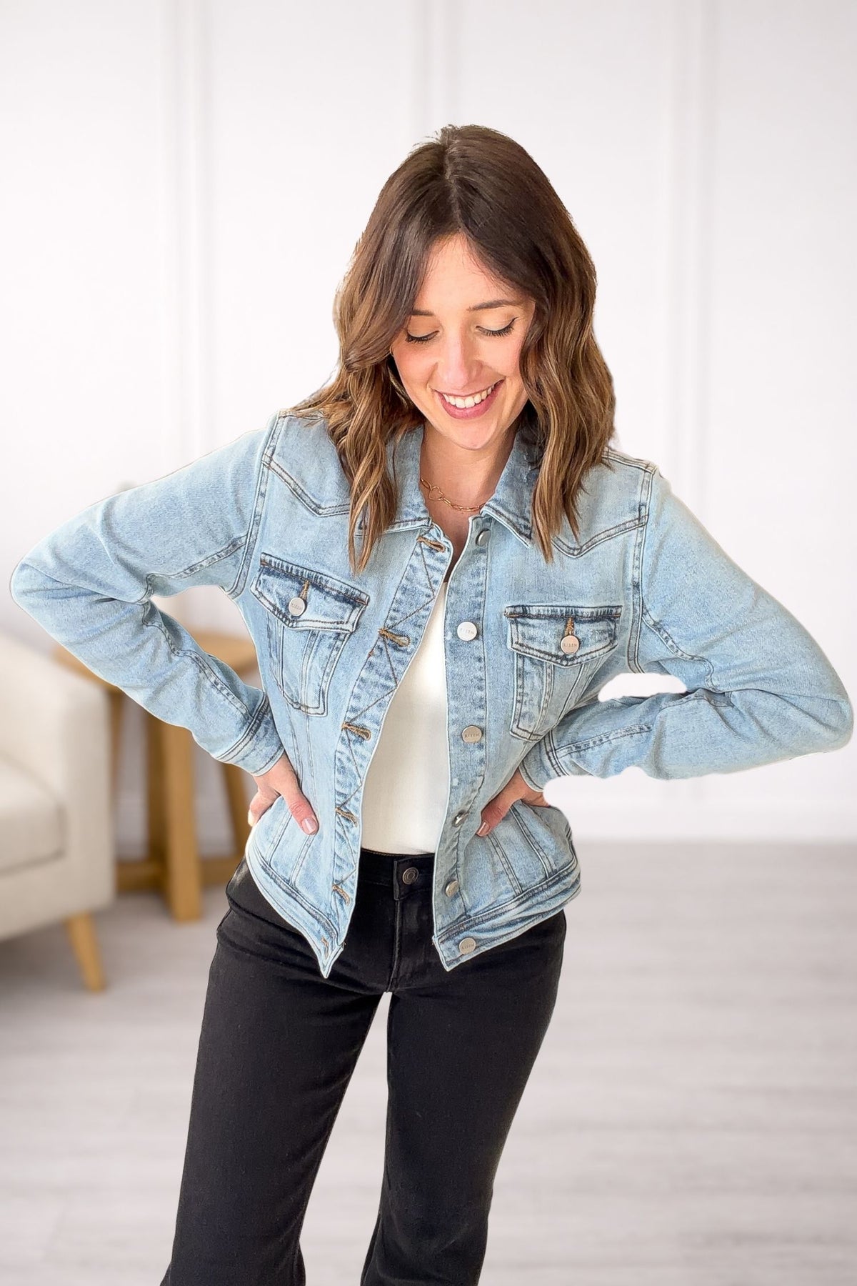 Woman wearing a light blue denim jacket indoors with a neutral background