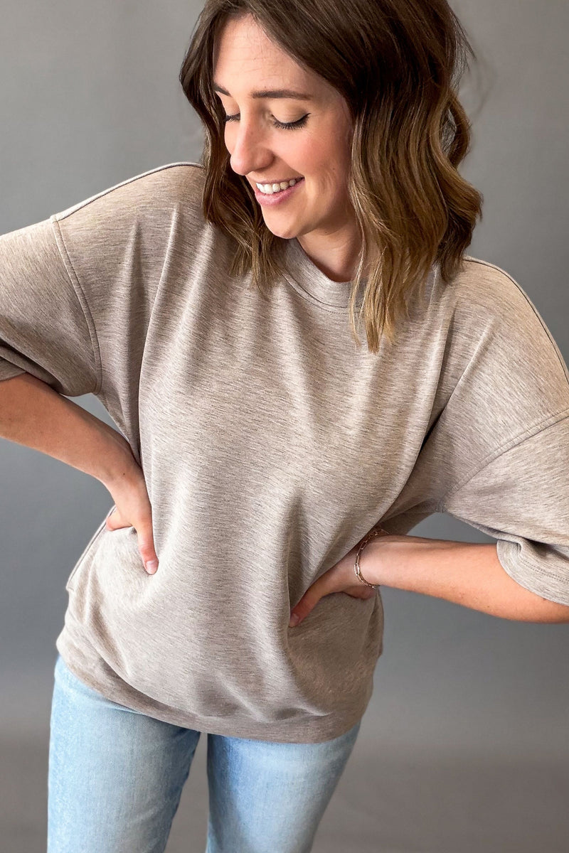 woman wearing a heather taupe short sleeve and blue jeans
