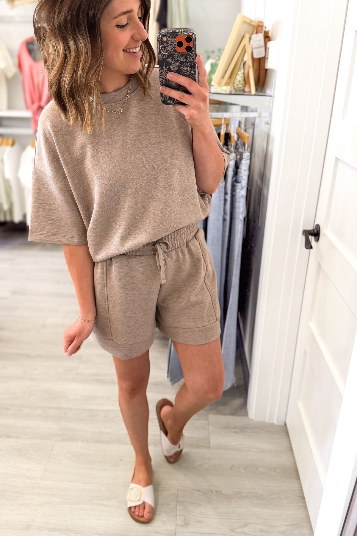 woman wearing a heather taupe lounge set in a boutique taking a selfie