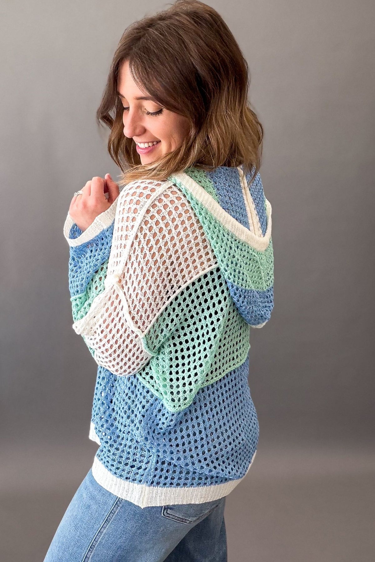 Woman wearing a colorful crochet pullover against a gray background