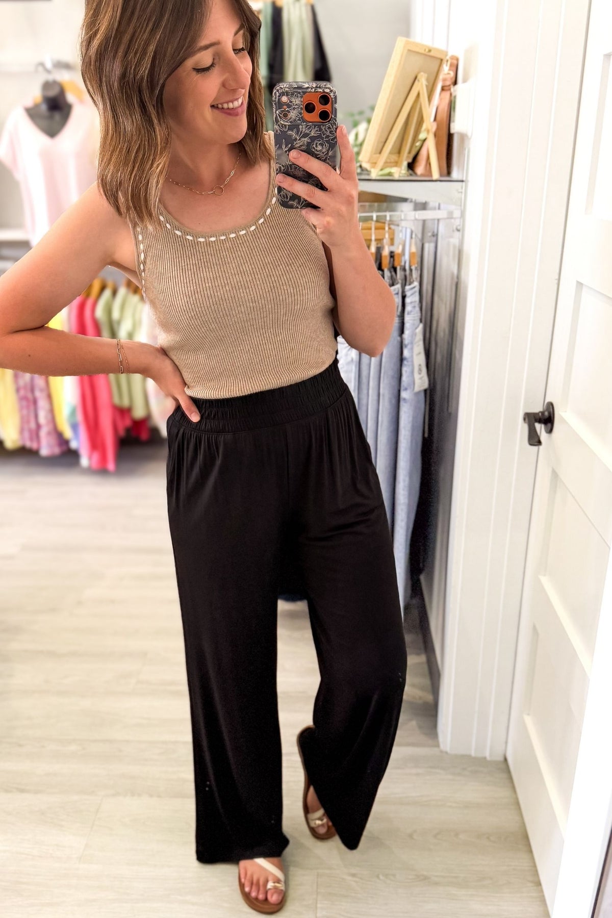woman taking a selfie wearing ultra-soft black wide leg pants with a stretchy elastic waistband and front pockets styled with sandals.