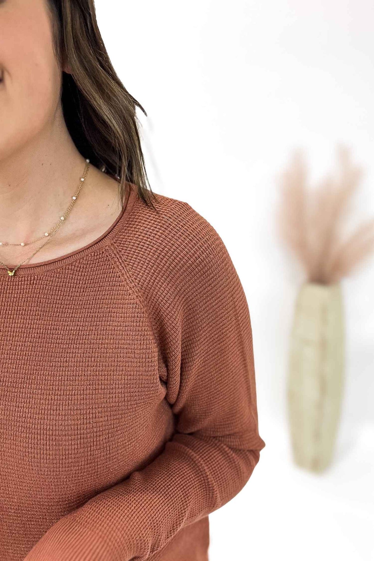 Person wearing a copper textured sweater with a blurred background