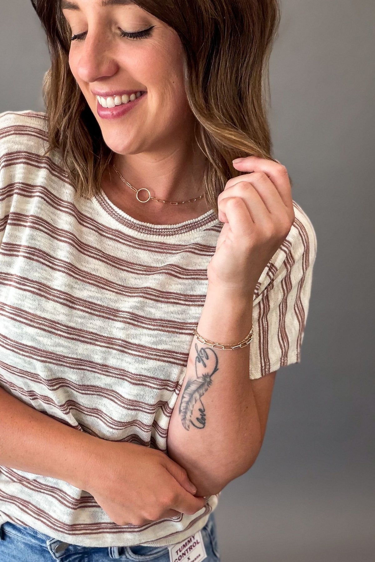 woman wearing a Lightweight ivory short sleeve tee with subtle copper pinstripes, a chest pocket, and a relaxed fit styled with light wash denim.