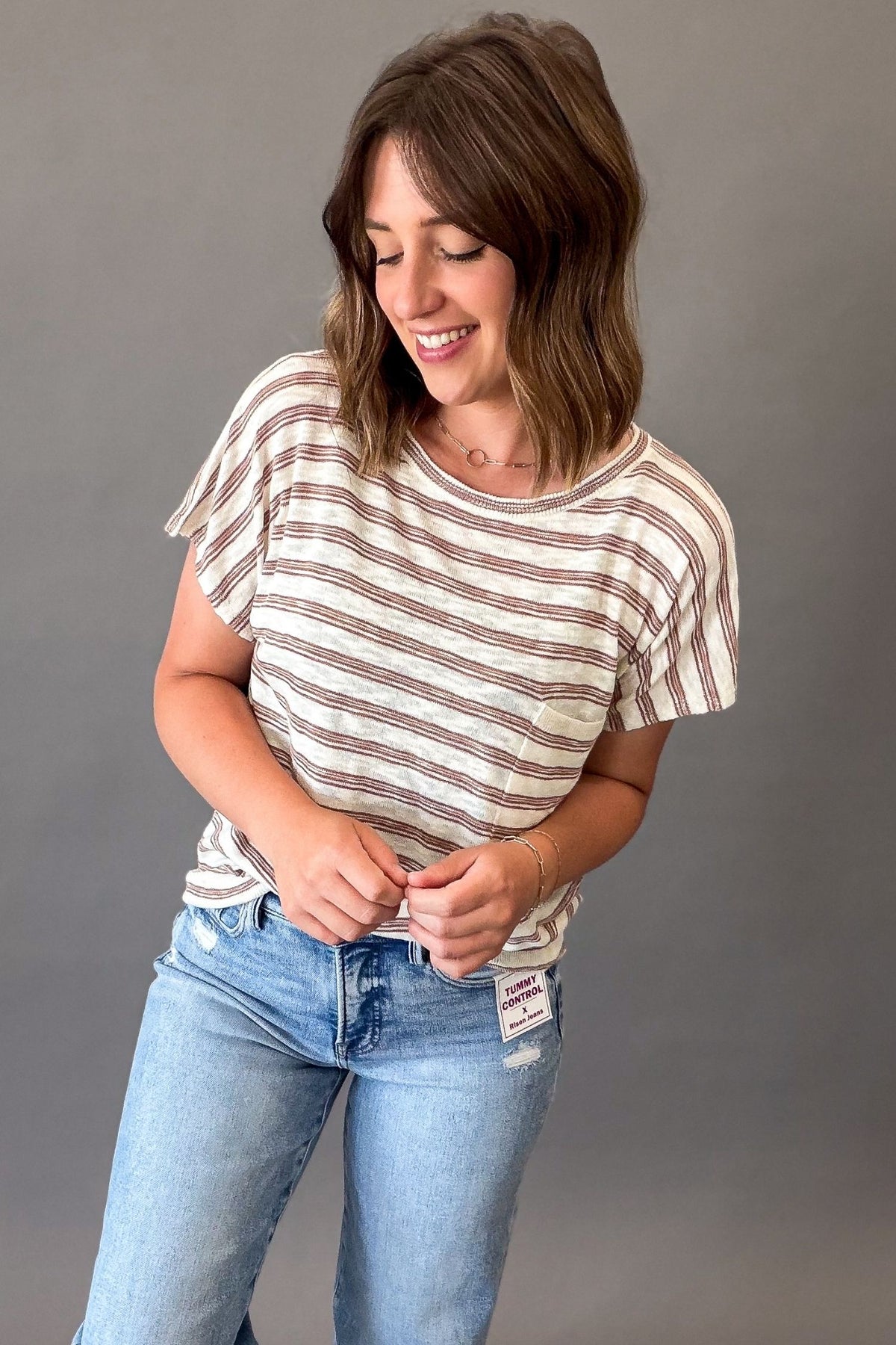woman wearing a Lightweight ivory short sleeve tee with subtle copper pinstripes, a chest pocket, and a relaxed fit styled with light wash denim.