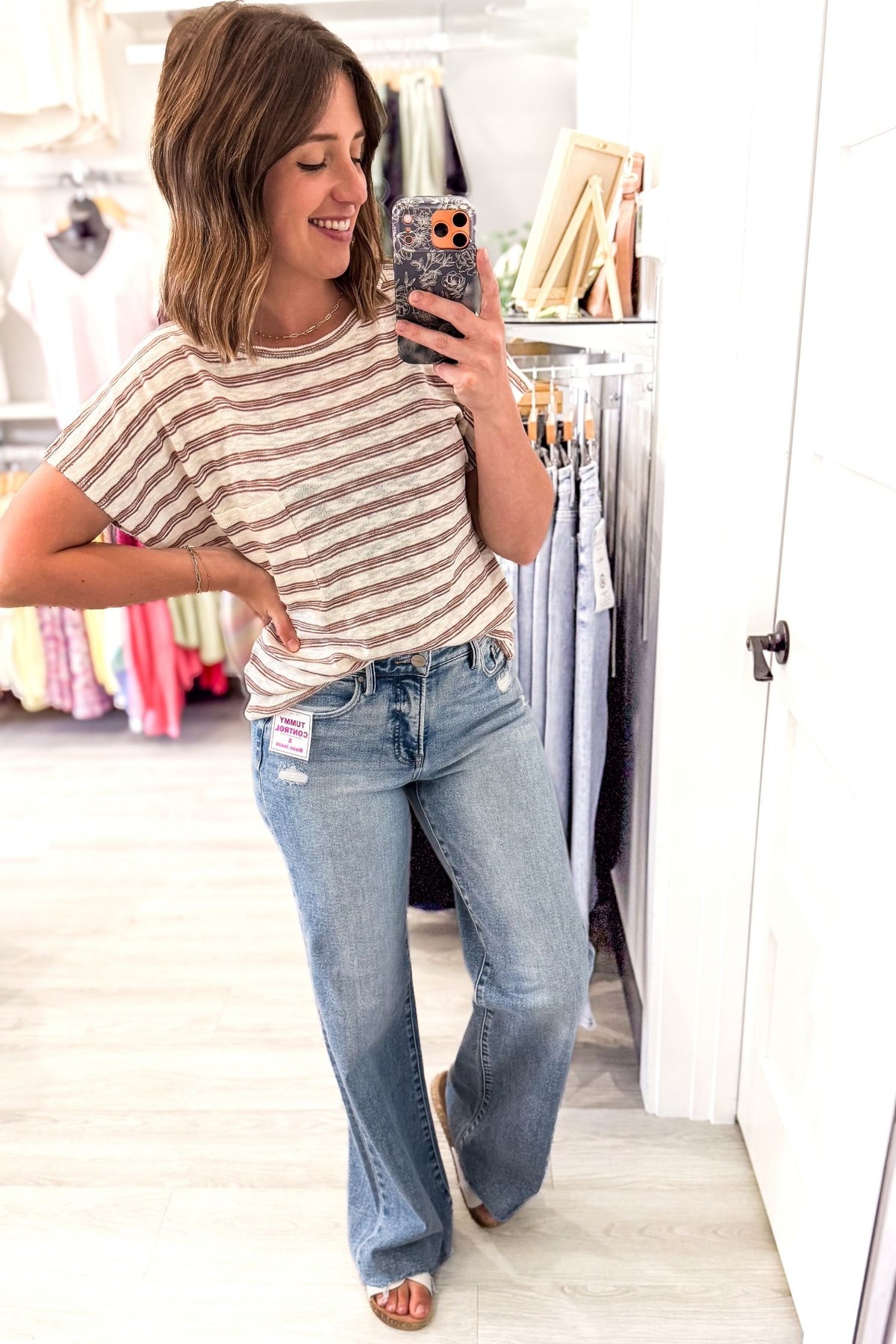 woman taking a mirror selfie wearing a Lightweight ivory short sleeve tee with subtle copper pinstripes, a chest pocket, and a relaxed fit styled with light wash denim.