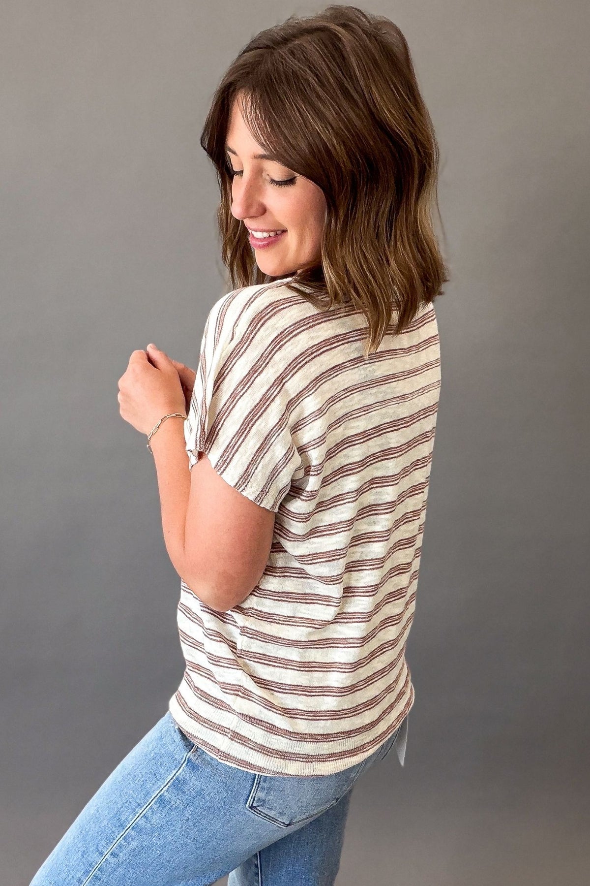 woman wearing a Lightweight ivory short sleeve tee with subtle copper pinstripes, a chest pocket, and a relaxed fit styled with light wash denim showing the side and back details