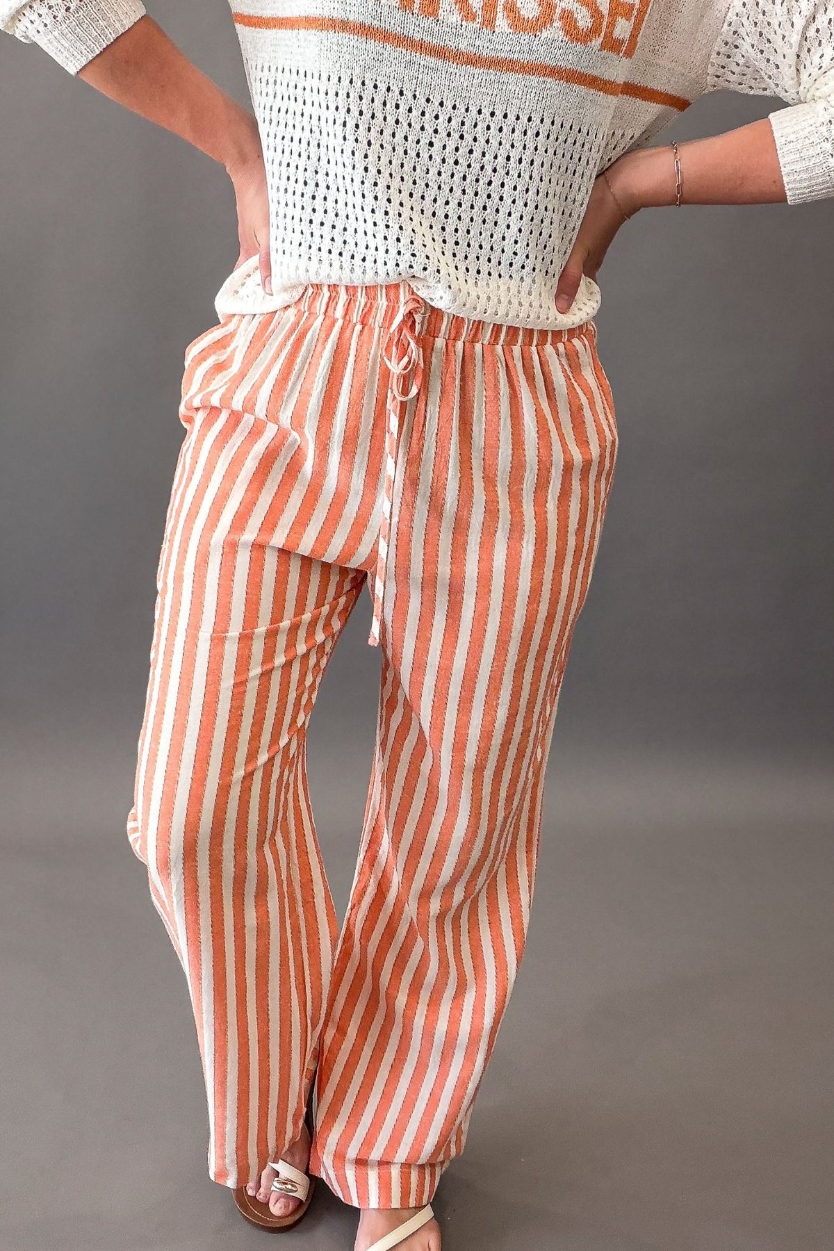 Person wearing a white and coral striped outfit with a plain background