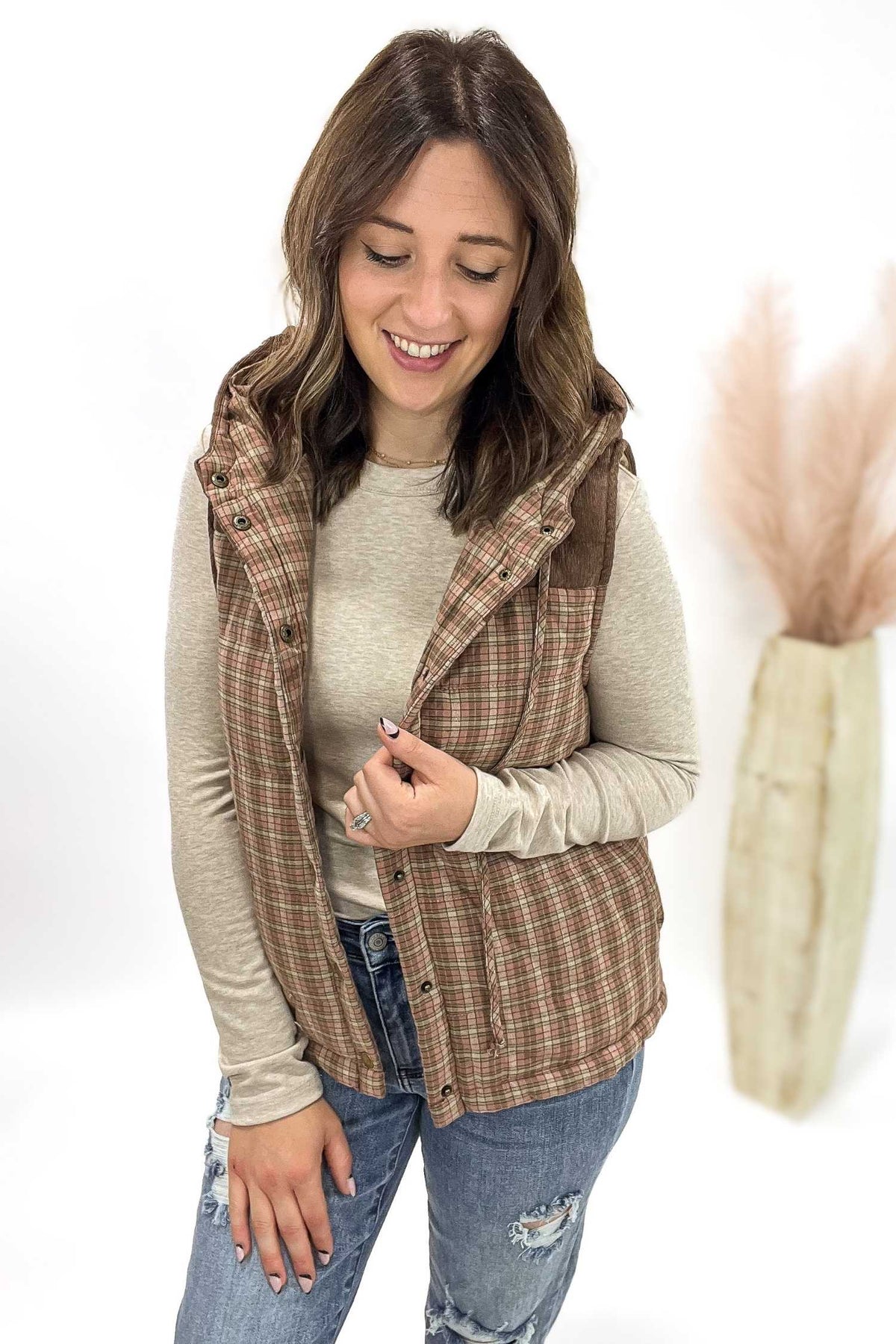 Woman wearing a plaid vest over a long-sleeve shirt with a white background