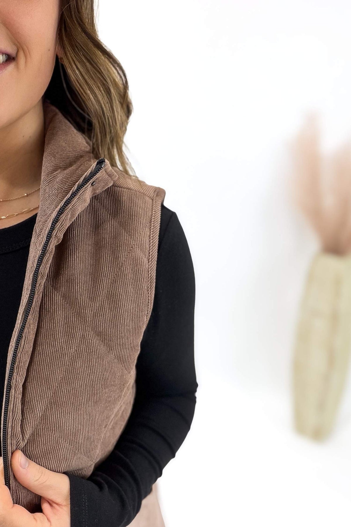 Person wearing a brown corduroy vest on a white background