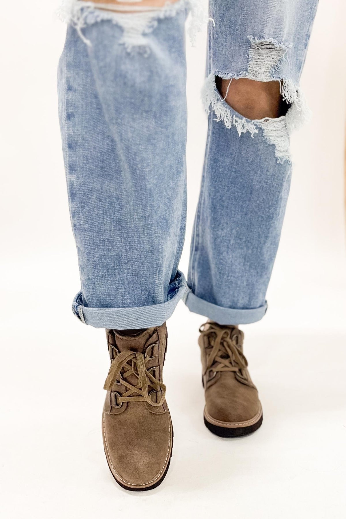 Ripped blue jeans with brown boots on a white background