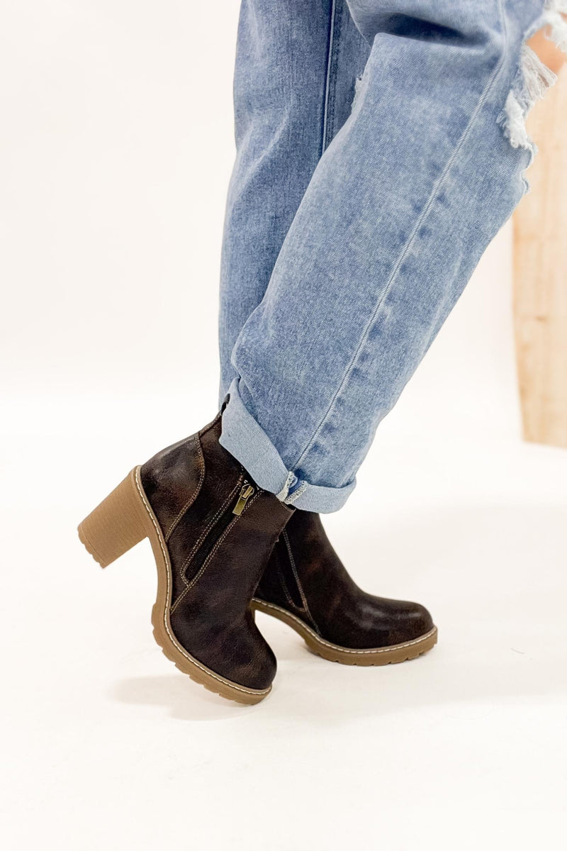 Brown ankle boots worn with light blue jeans on a white background