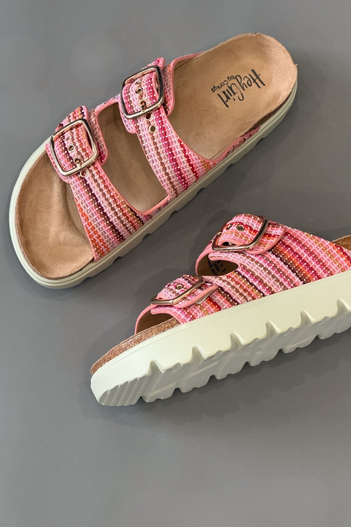 Pink sandals with white soles on a gray background