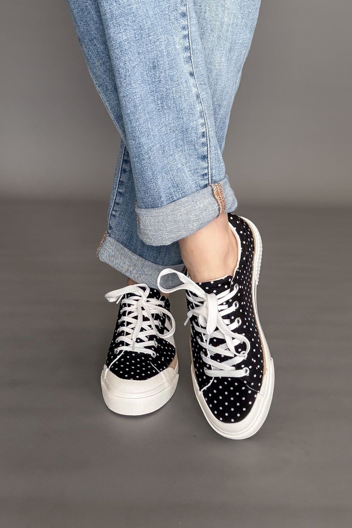 Woman wearing Corkys That’s Her polka dot sneakers styled with light wash boyfriend jeans.