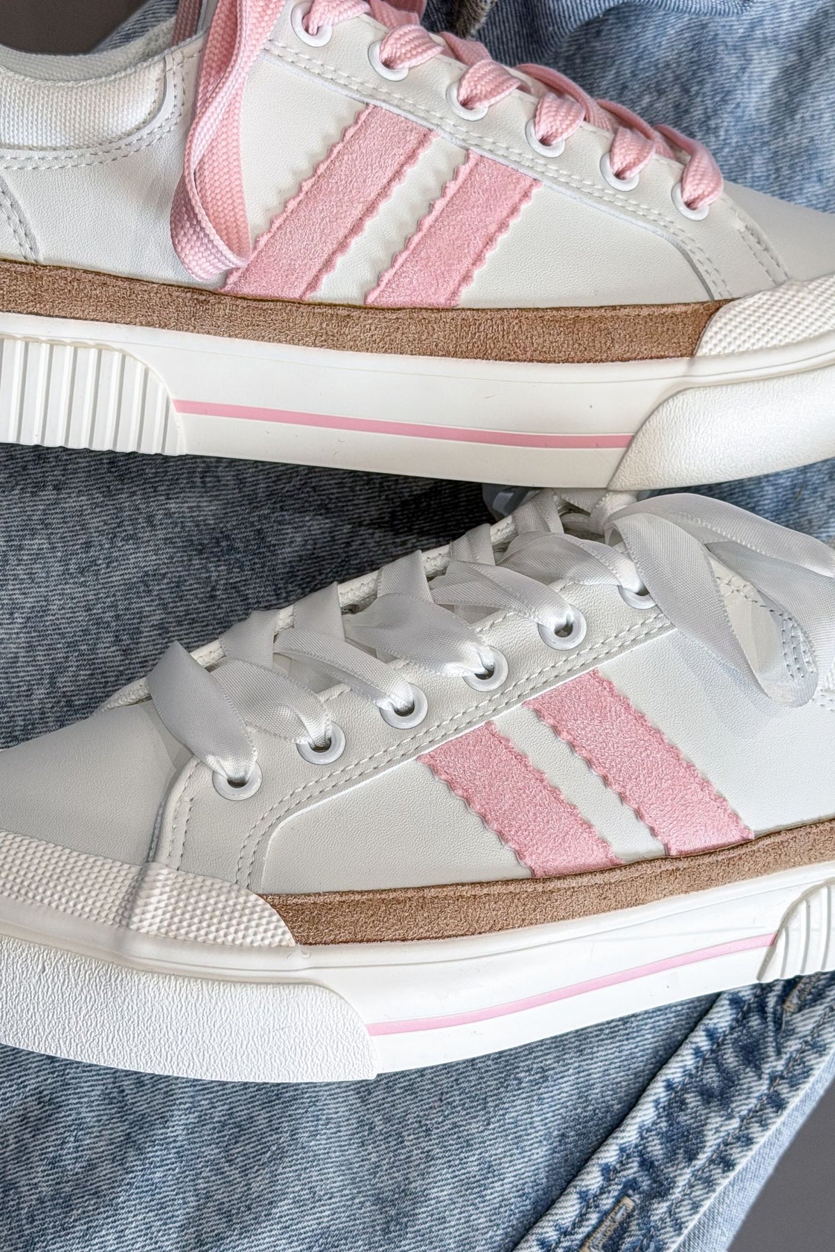 White sneakers with pink stripes on a denim background
