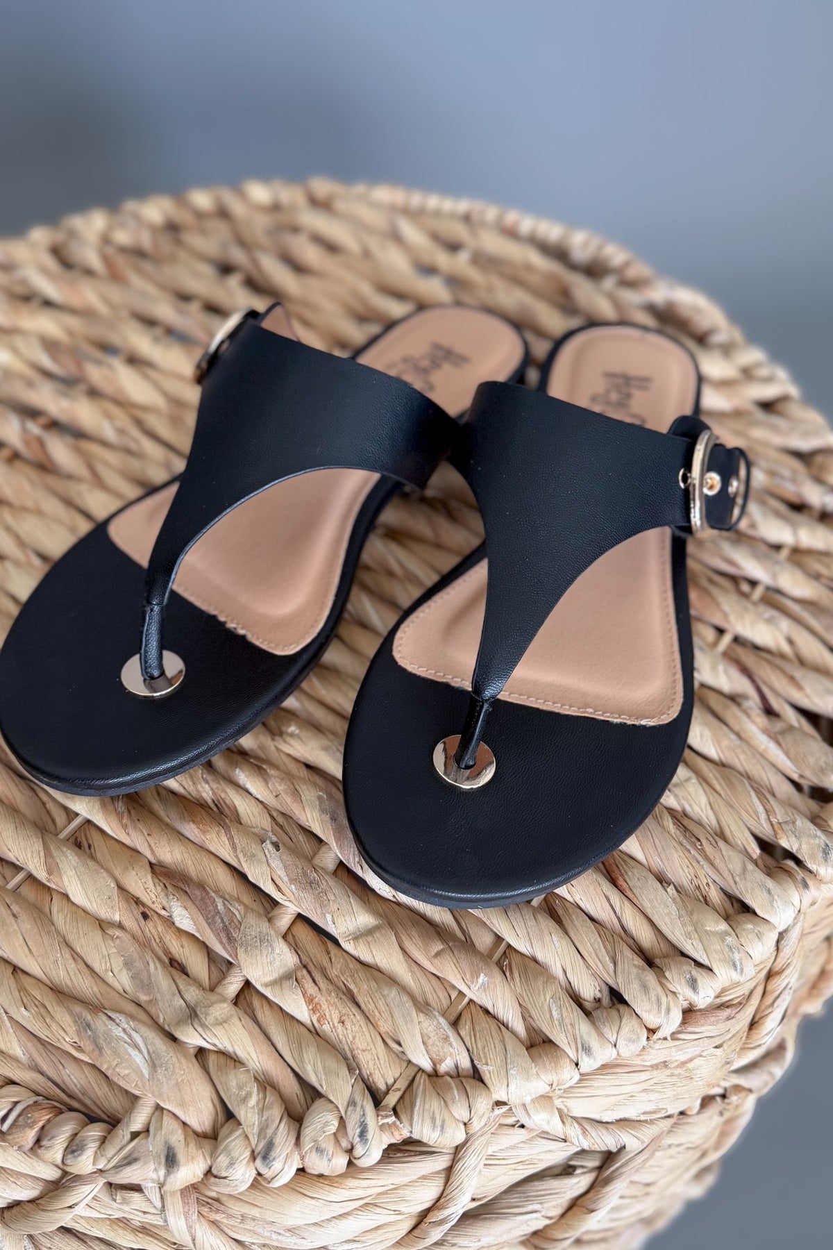 Black sandals on a woven surface with a blurred background