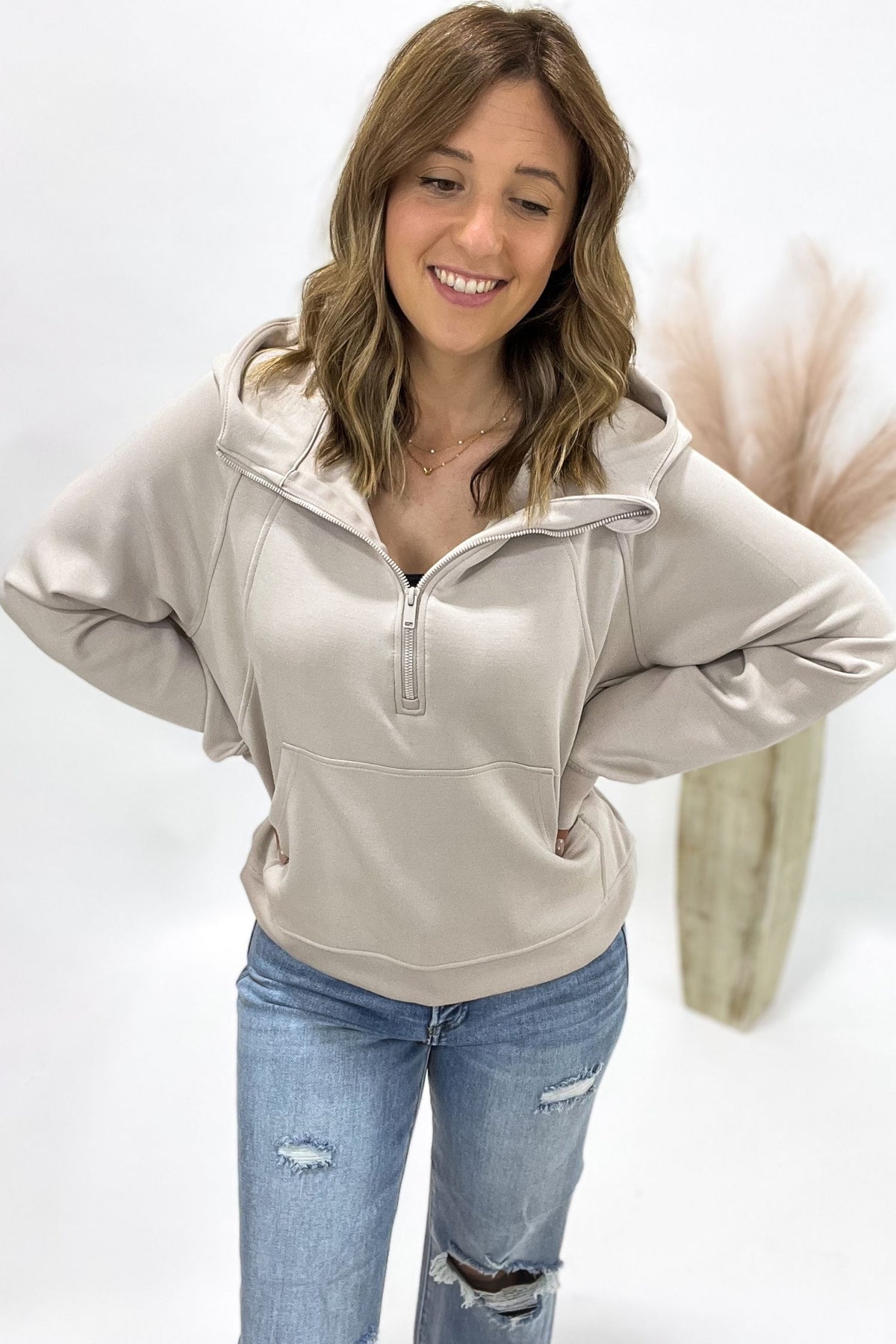 woman wearing a cream half zip standing in front of a white background