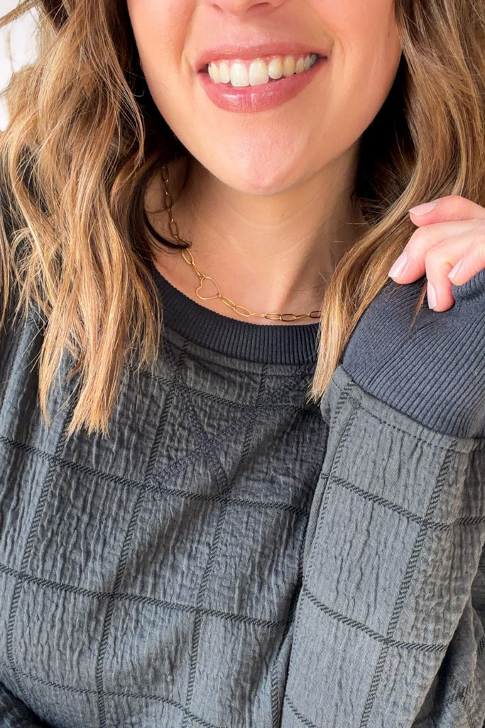 Person wearing a textured gray sweater with a close-up of the neckline.