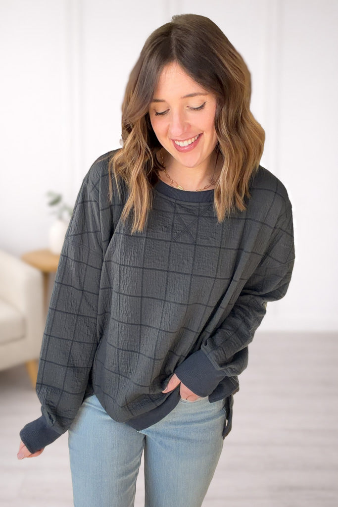 Woman wearing a gray oversized sweater and light blue jeans indoors.